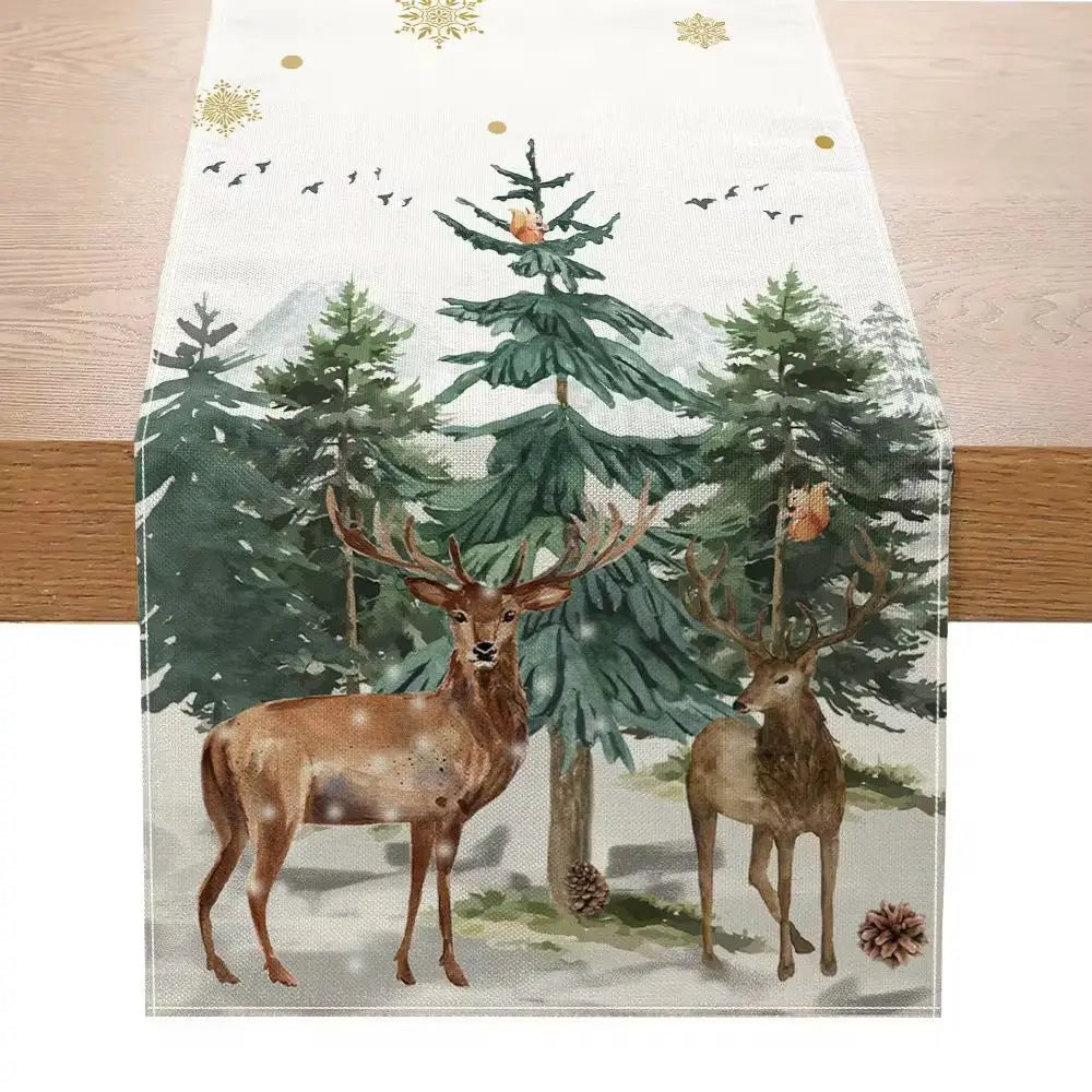 A white linen Christmas table runner measuring 183 by 33 inches featuring a watercolor-style winter forest scene with two brown deer green pine trees and gold snowflakes.