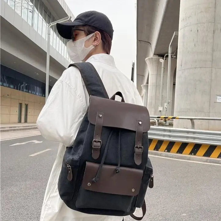 Black canvas retro backpack with brown leather accents and buckle straps featuring large capacity and wear resistant material.