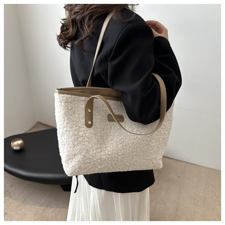 Cream-colored plush faux fur tote bag with tan leather handles and accents shown as the front view of a brown faux fur tote bag with leather straps.