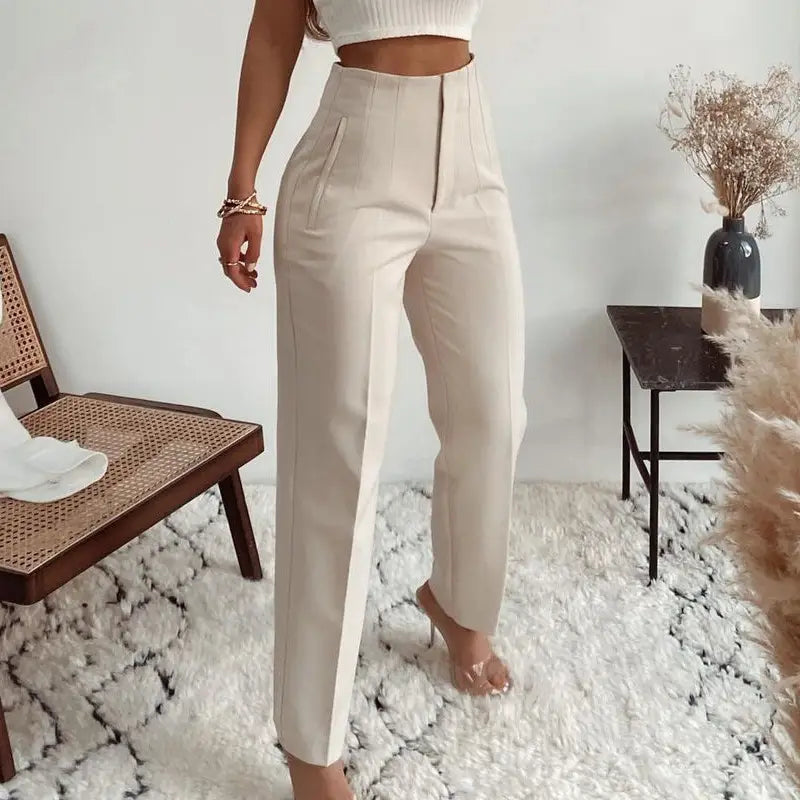 Pantalon taille haute à plis plats et jambes droites de couleur crème, avec une coupe soignée élégante et des plis verticaux discrets le long de l’avant.