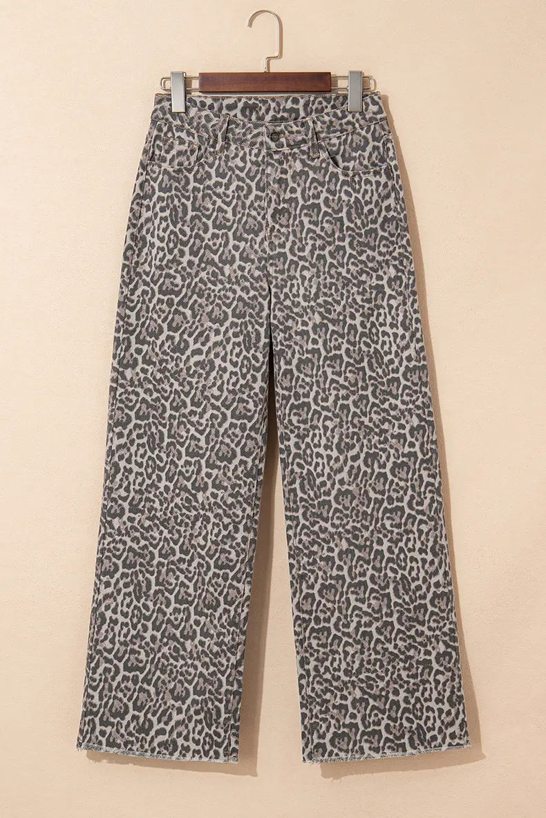 Jean en denim à taille haute évasée en imprimé léopard gris et noir, avec ourlets effilochés pendus sur un cintre en bois.