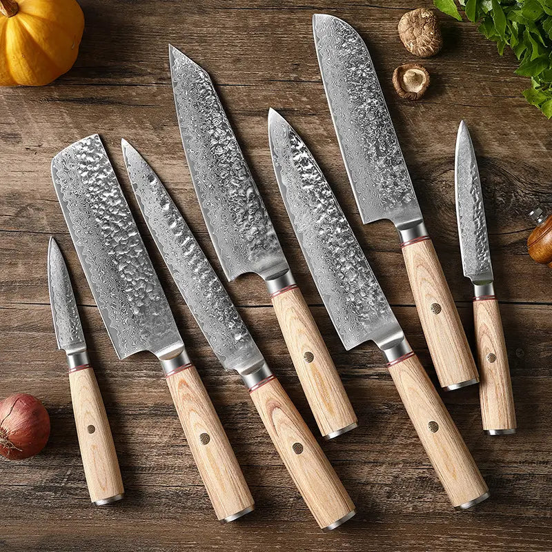 Juego de siete cuchillos de chef con hojas de acero damasco y mangos de madera clara martillados.