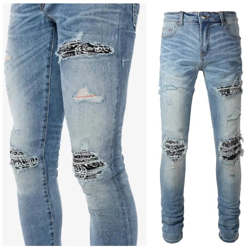 Men’s slim fit light wash denim jeans with distressed ripped knees and thighs featuring black and white bandana style patches.