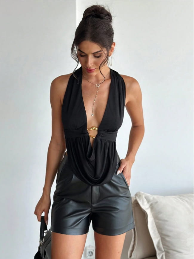 black satin halter romper featuring a deep plunging neckline and faux leather shorts in a sleek black color.