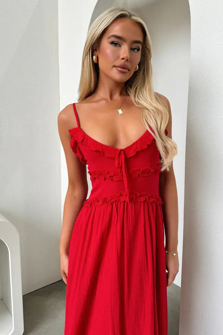 A vibrant red ruffled sleeveless flowing maxi vacation dress with spaghetti straps and a tied front detail.