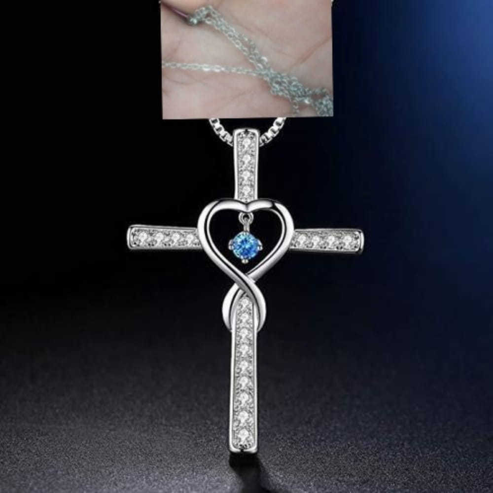 Silver cross pendant necklace featuring a heart-shaped center with a blue birthstone gemstone and clear crystals along its arms in the infinity love heart cross birthstone crystal necklace design.