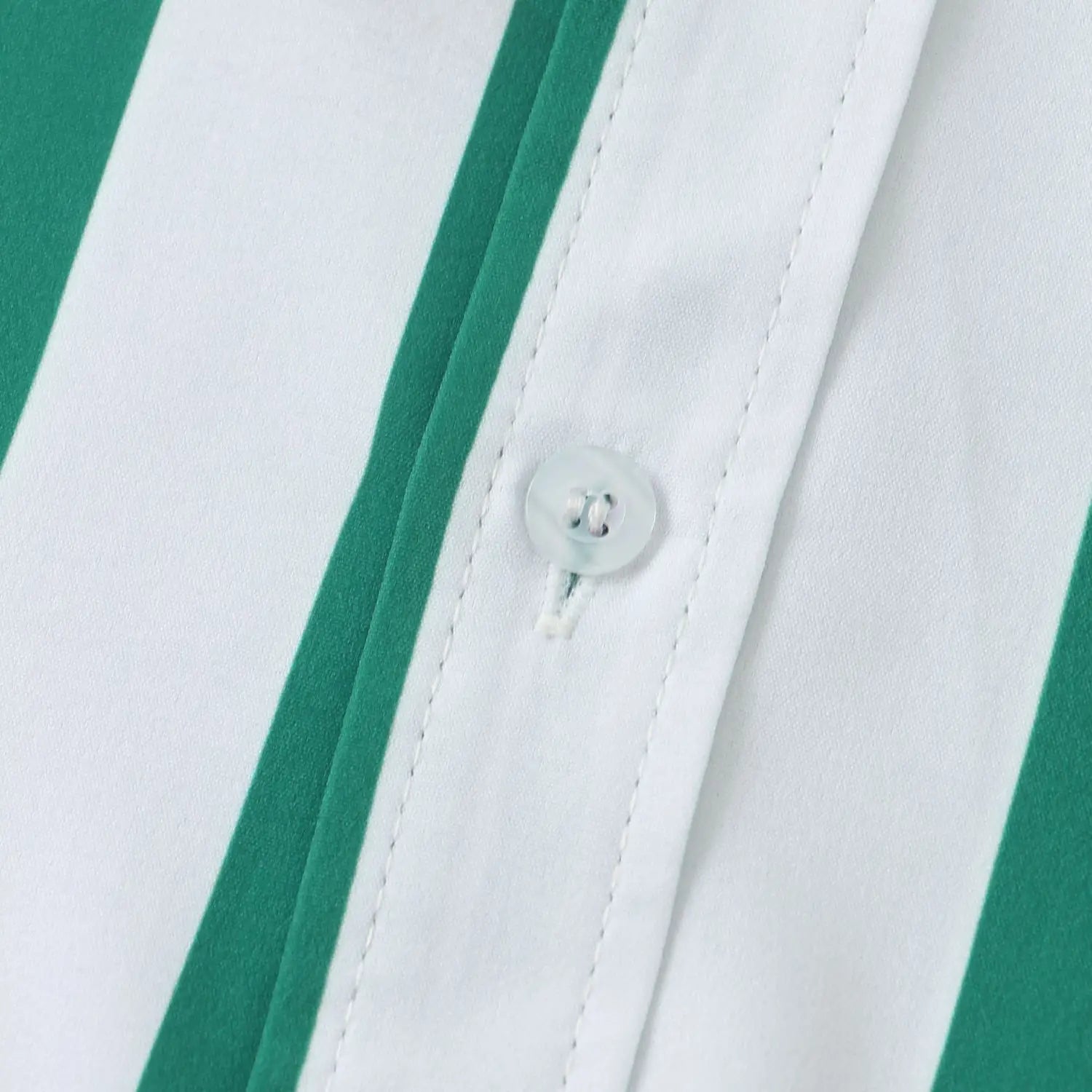 Un bouton blanc translucide sur une chemise pour homme à rayures, à manches courtes, rayée vert et blanc.