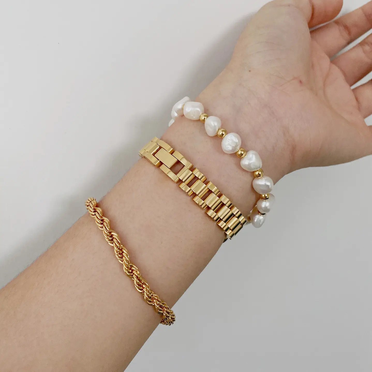 Elegant gold titanium link bracelet with delicate white pearl accents and gold-toned spacer beads in a classic and elegant design.