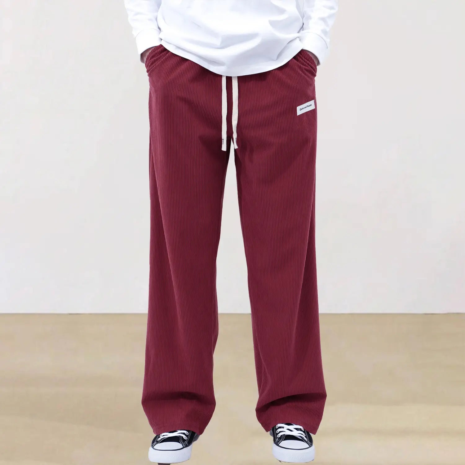 Men’s slim fit sporty drawstring casual pants in maroon corduroy with a white drawstring and small rectangular brand patch on the waistband.