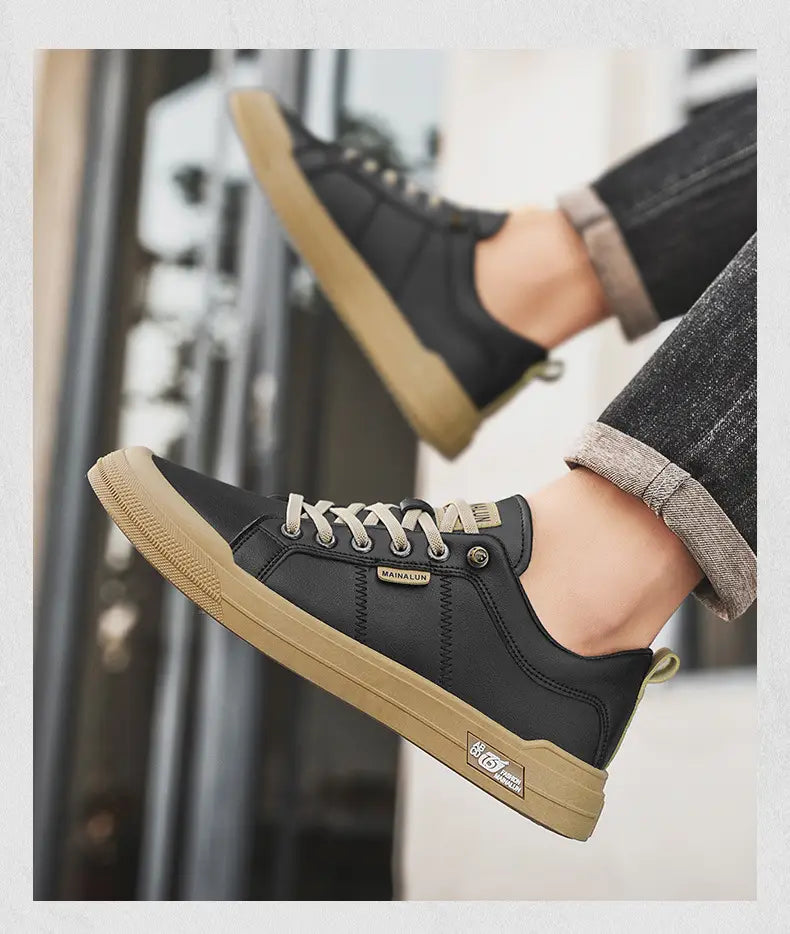 men’s white minimalist leather casual sneakers featuring black leather low-top design with tan rubber soles and matching laces with a subtle brand patch on the side.