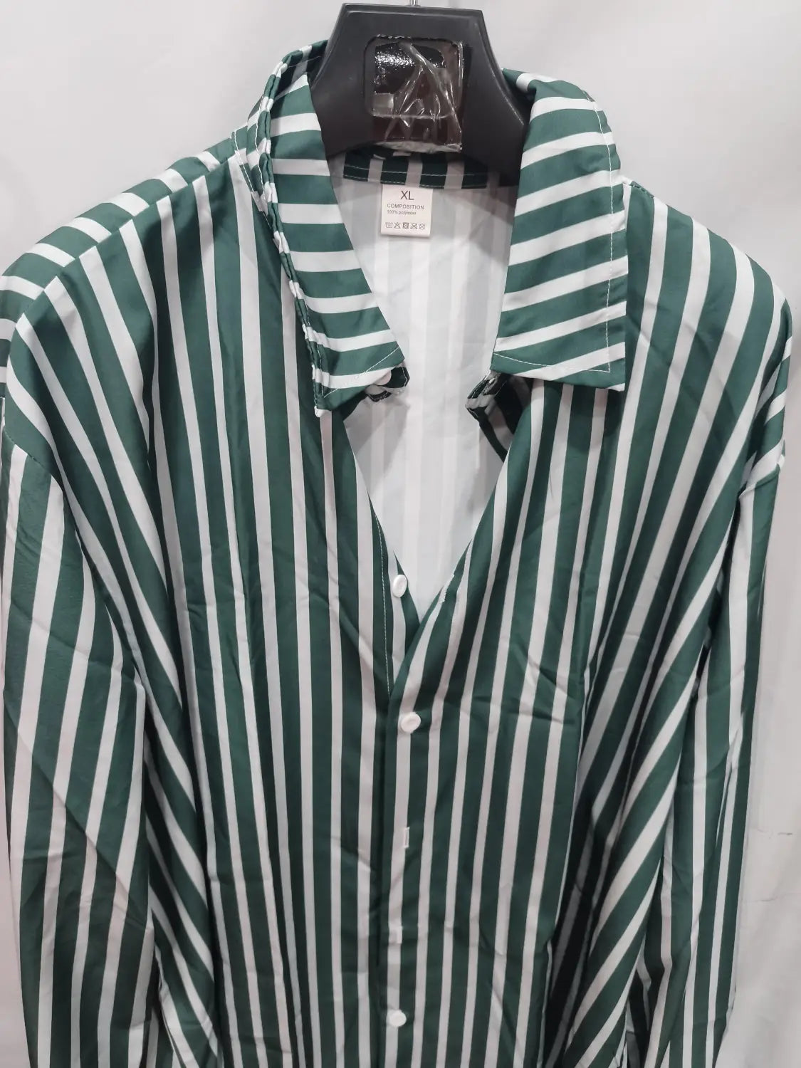 Chemise décontractée à manches longues rayée verticalement vert et blanc pour hommes, à patte boutonnée et col, suspendue sur un cintre noir.