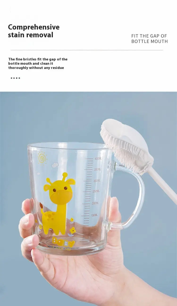 Clear glass measuring cup with yellow giraffe design and measurement markings held beside a white cup brush long handle glassware cleaning tool.