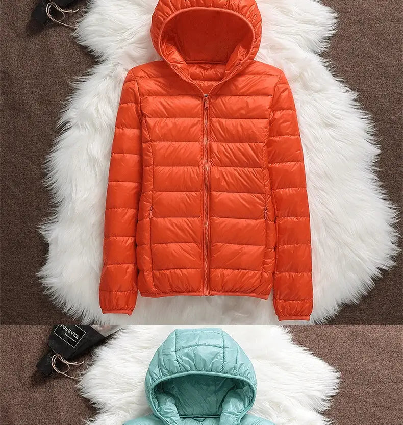 Bright orange women lightweight down hooded puffer jacket with horizontal stitching displayed on a white faux fur surface.