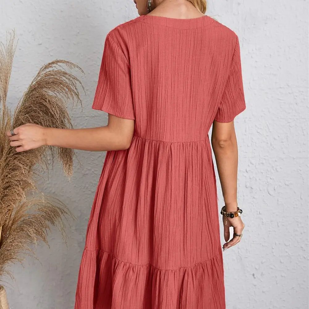 Une robe midi à étages de couleur corail, en tissu texturé, à manches courtes, conçue comme une robe d’été trapèze évasée à encolure en V pour femmes.