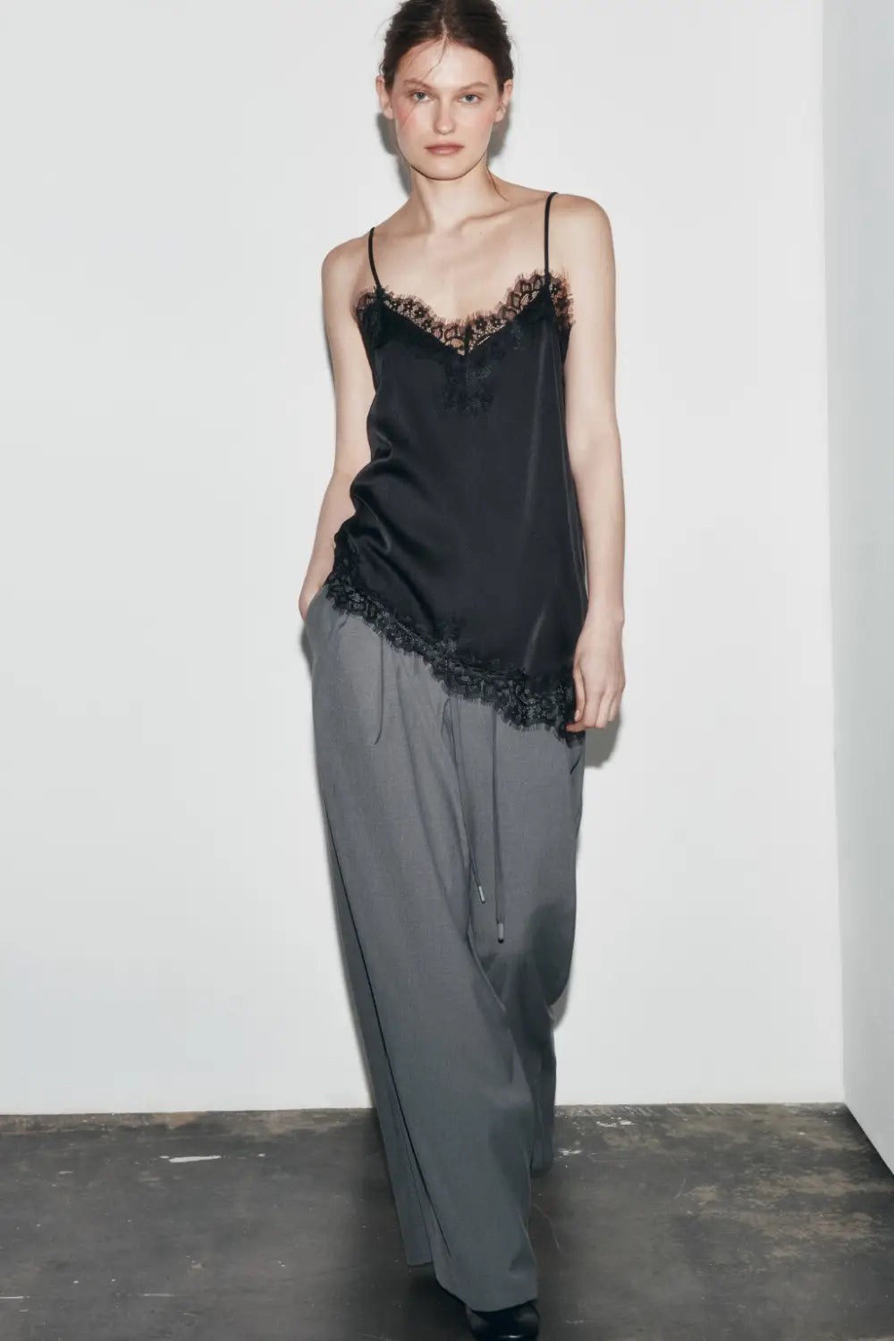 Schwarzes Satin-Camisole-Top mit zartem Spitzenbesatz entlang des Ausschnitts und Saums.