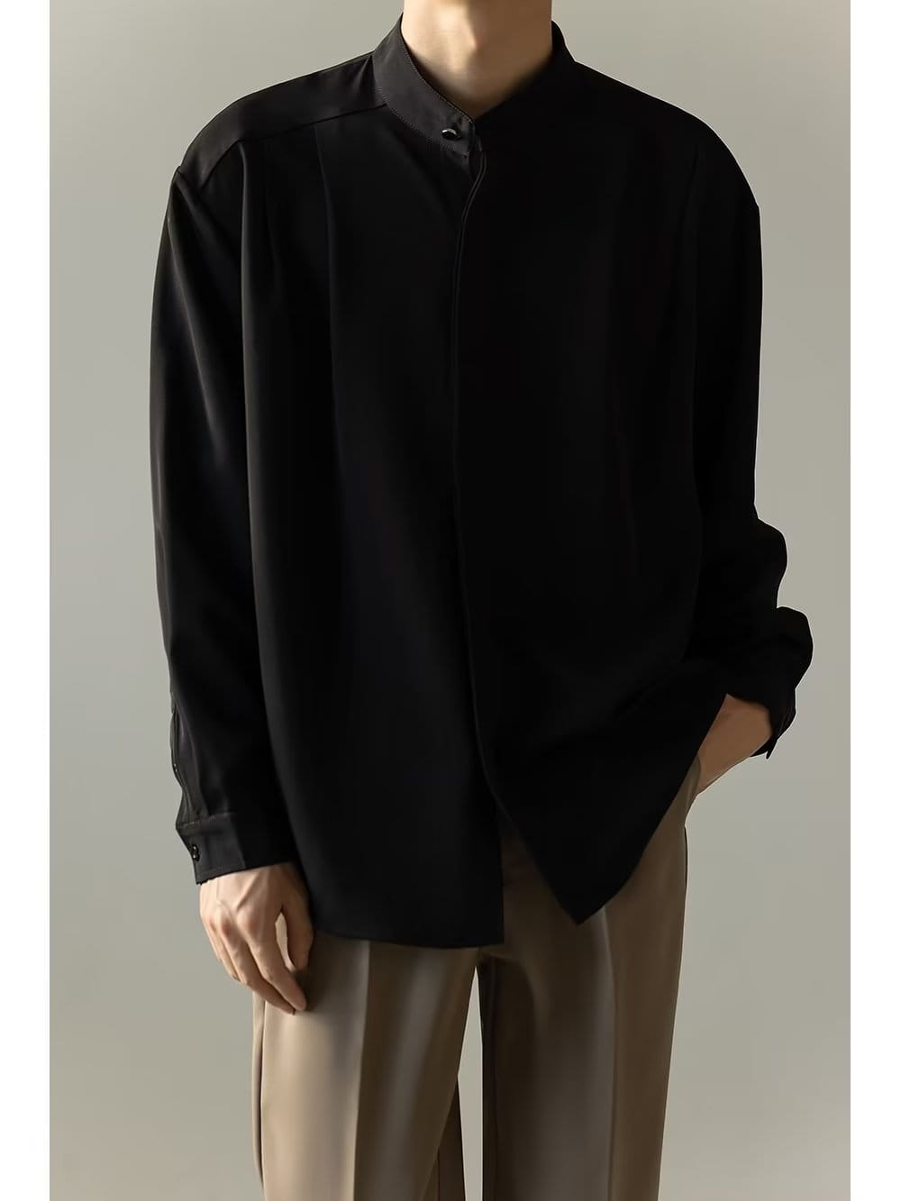 Chemise plissée pour homme à col montant noire, à manches longues, avec des plis d’épaule subtils réalisés dans un tissu souple.