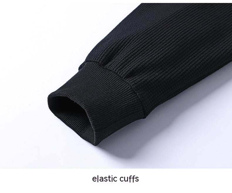 black ribbed elastic cuff on the sleeve of a waffle hooded sportswear set made from textured fabric.