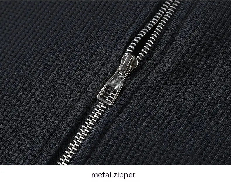 Silver metal zipper on black textured ribbed fabric of waffle hooded sportswear set.