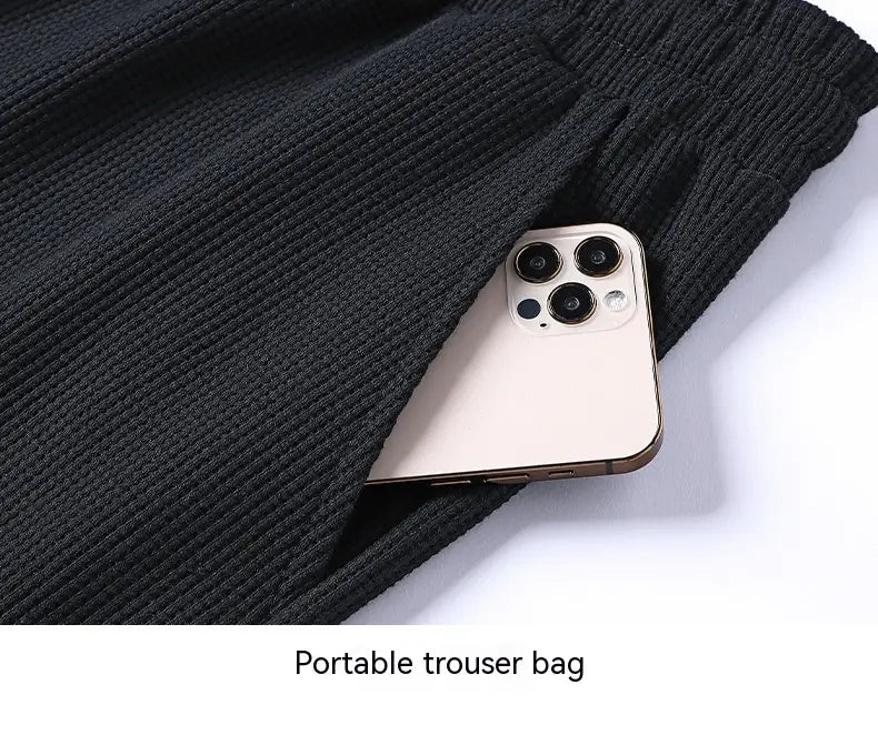 black ribbed knit portable trouser bag with a smartphone in the pocket featured in the waffle hooded sportswear set