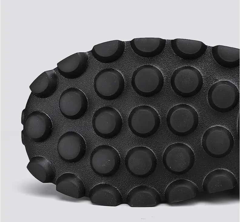 black rubber sole with a pattern of raised circular studs on men’s black crocodile embossed leather sneakers