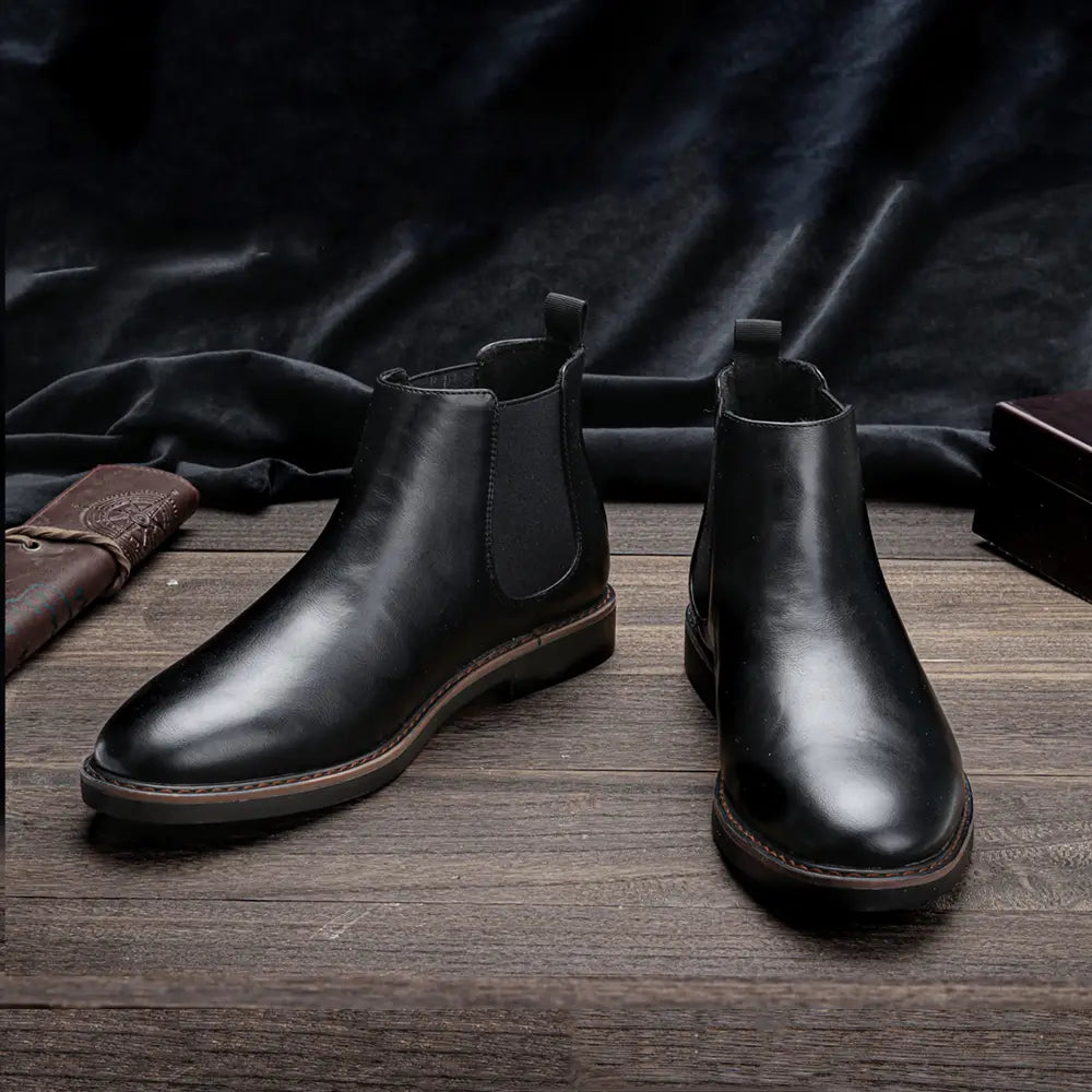 Herren wasserdichte Leder-Chelsea-Boots in Schwarz mit glatter, polierter Oberfläche und kontrastierenden braunen Sohlen.