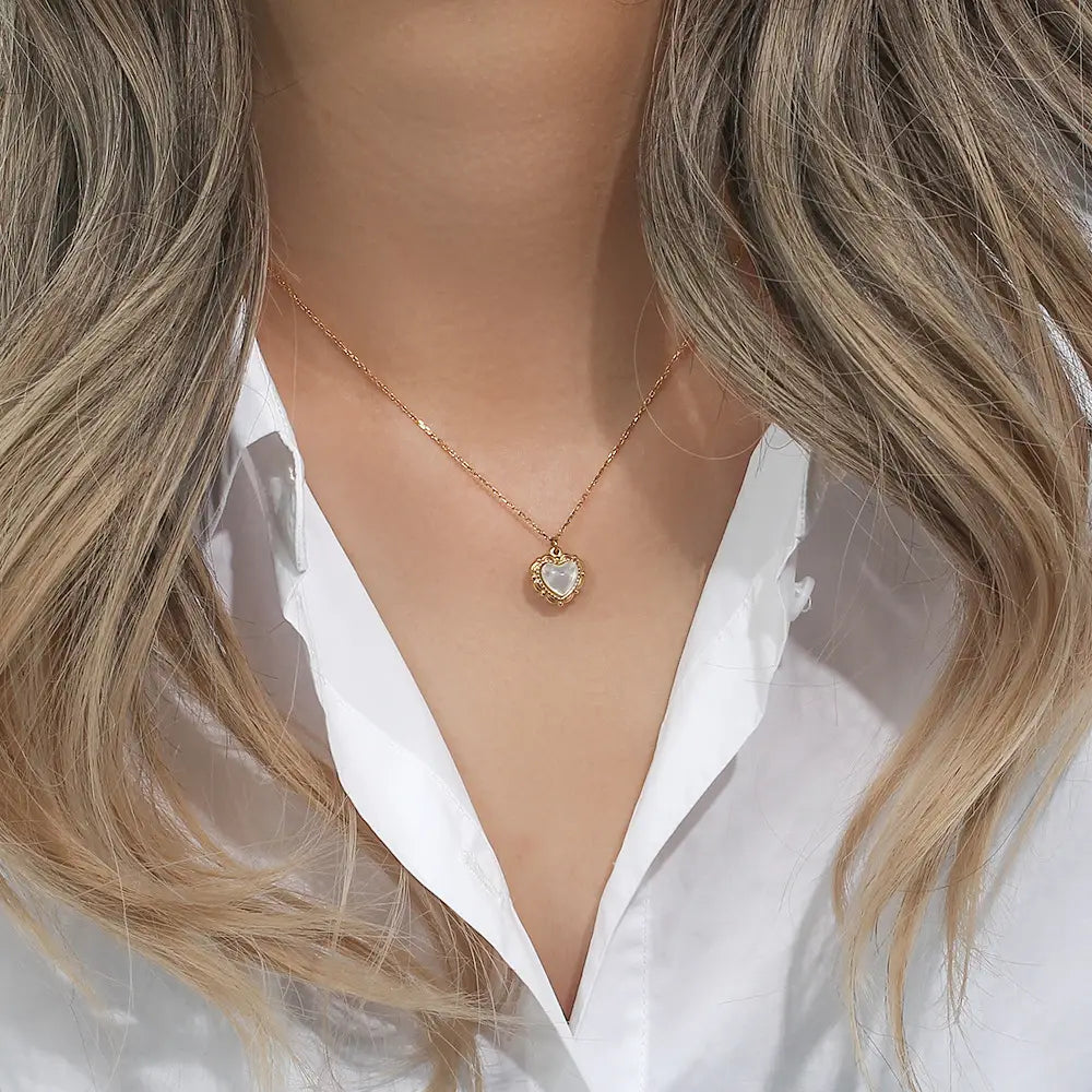 A delicate vintage shell heart pendant necklace in 18k gold plated featuring a central white gemstone.