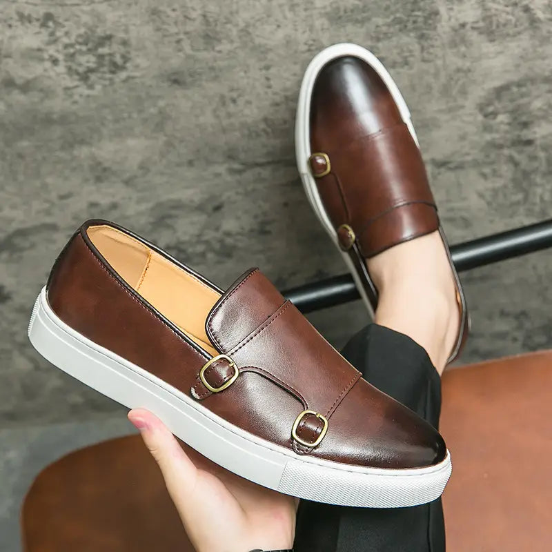 Baskets en cuir pour homme style business casual à double boucle en marron, avec détails de boucle ton or et semelle en caoutchouc blanc.