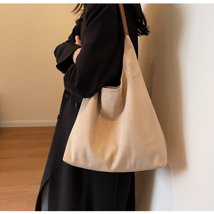 Beige suede shoulder bag with a large capacity and soft slouchy canvas design featuring a matching tan strap.
