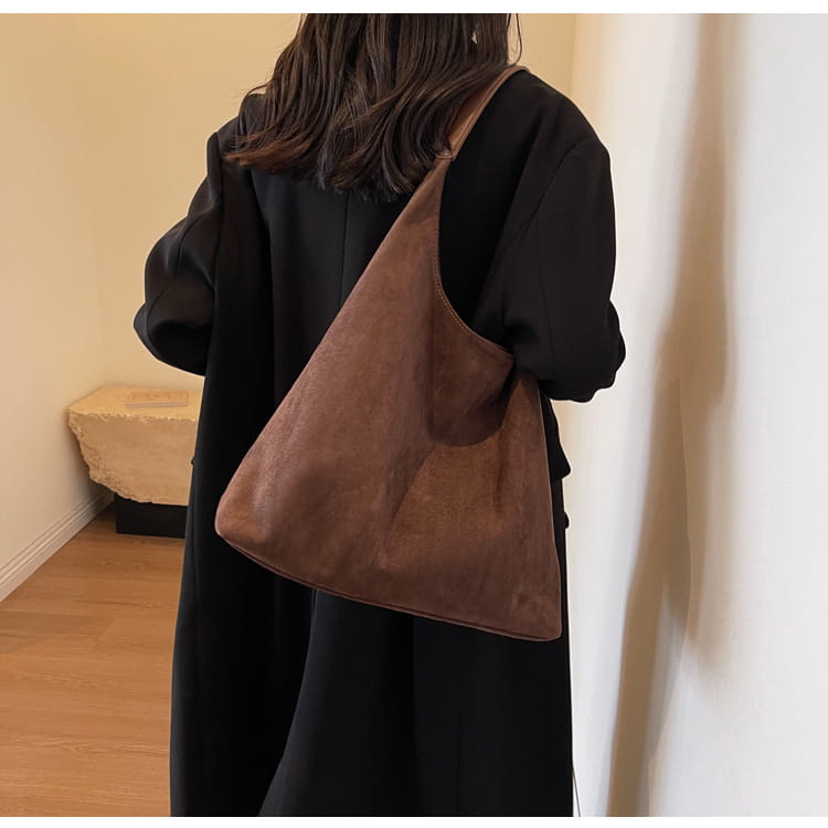 Brown suede shoulder bag with a large capacity and slouchy tote design in a minimalist style.