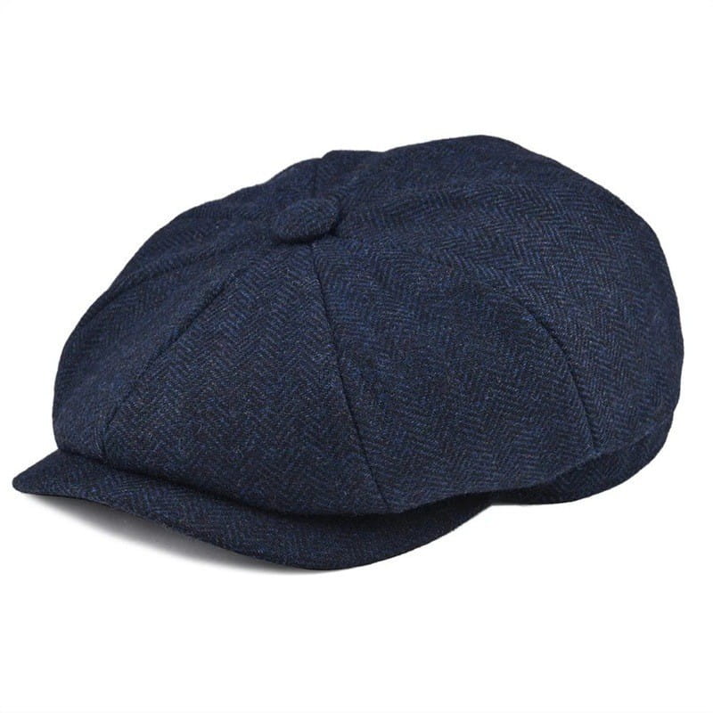 Dark blue herringbone wool newsboy hat for men with a structured eight-panel flat cap design and small button on top.