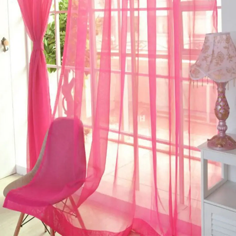 Bright pink sheer tulle window curtains with a delicate flowing design hang gracefully to frame the window for living room and bedroom use.