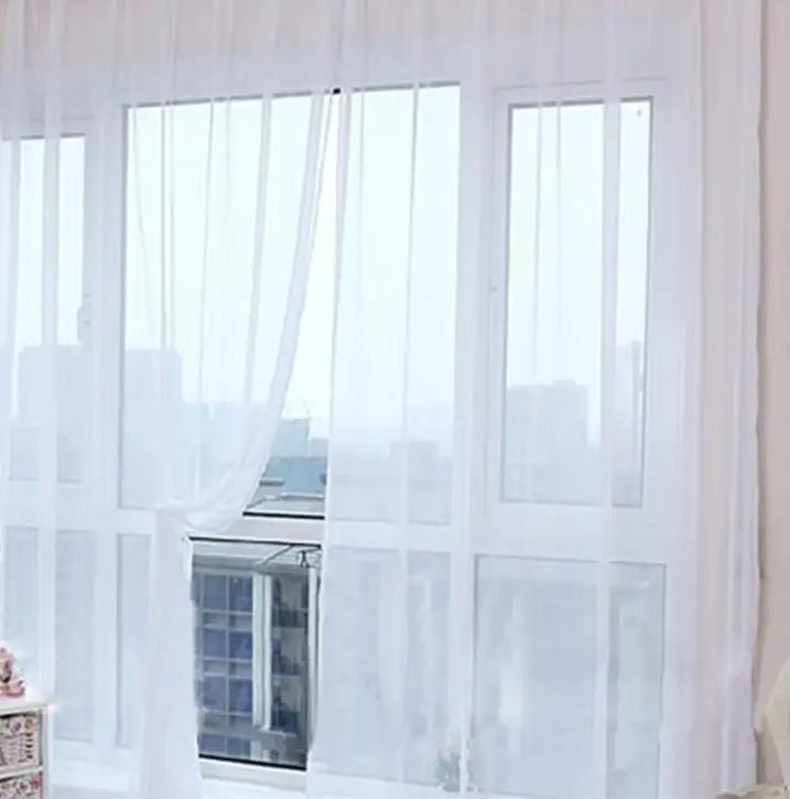 Delicate white sheer tulle window curtains with a subtle vertical pleated design gently draped to frame a living room or bedroom window.