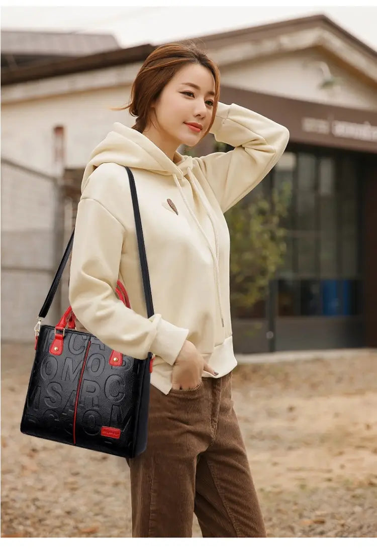 Large capacity leather embossed shoulder bag in black with red accents and visible embossed lettering.