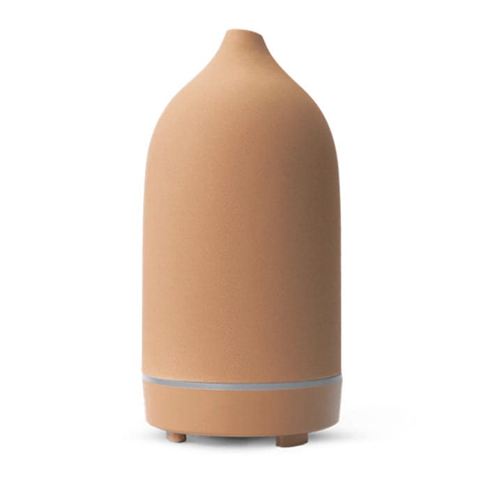 Ceramic ultrasonic aroma diffuser and humidifier in tan ceramic with a sleek rounded body and subtle silver accent band near the base.