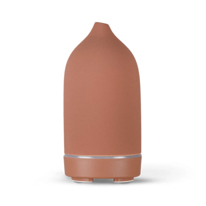 Terracotta-colored ceramic ultrasonic aroma diffuser and humidifier with a sleek rounded design and a subtle metallic accent band near the base.