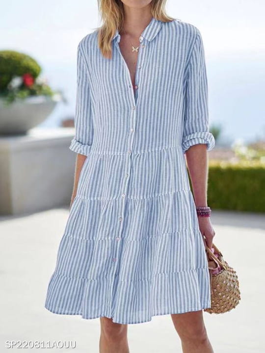 Robe chemise à rayures verticales bleu clair et blanc, boutonnée, avec col à revers, manches trois-quarts retroussées et jupe à volants étagés.
