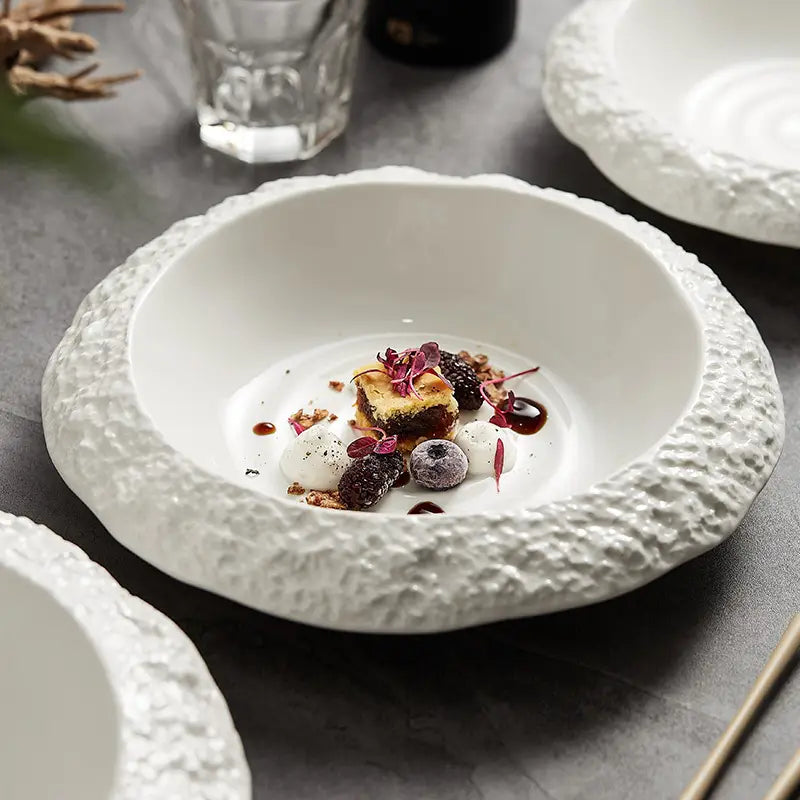 White ceramic deep plate with a modern rock pattern featuring a textured bumpy rim and a smooth interior.