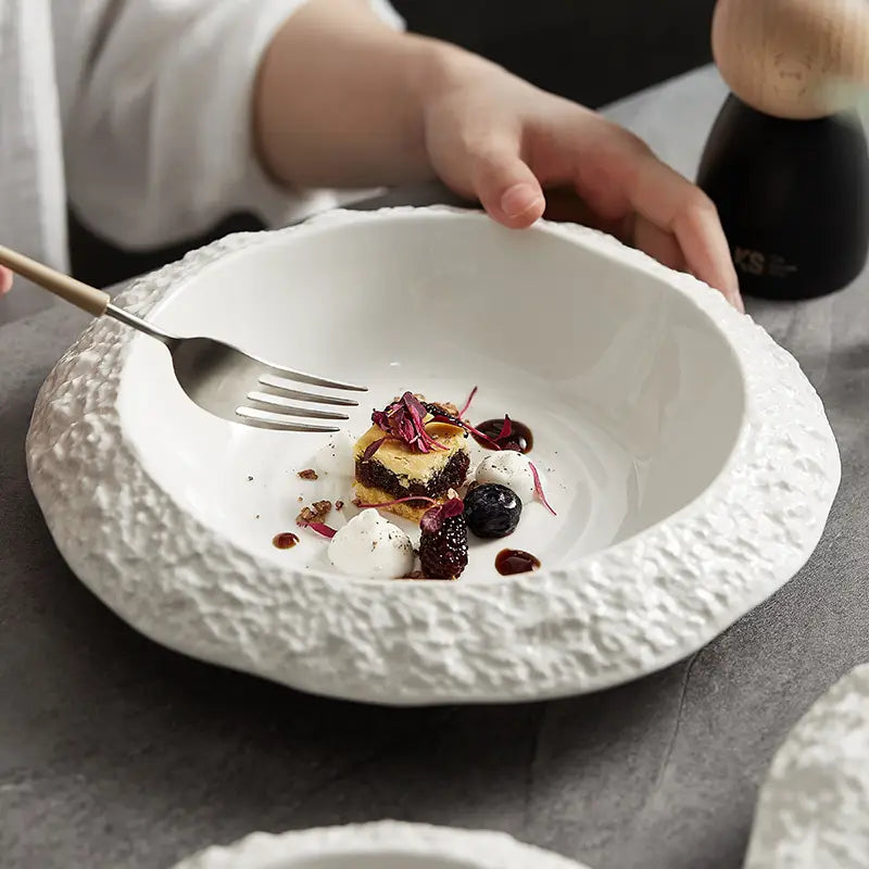 White ceramic deep plate with a textured rocky exterior and smooth interior in a modern white bowl design.