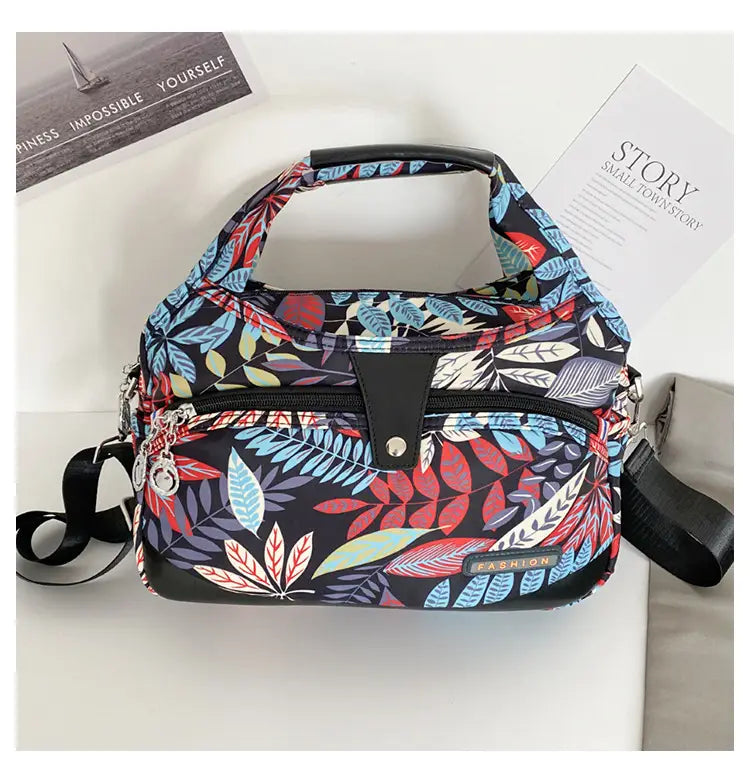 Oxford cloth floral messenger bag with a black base and vibrant red blue and white leaf-patterned design for retro shoulder purse use.