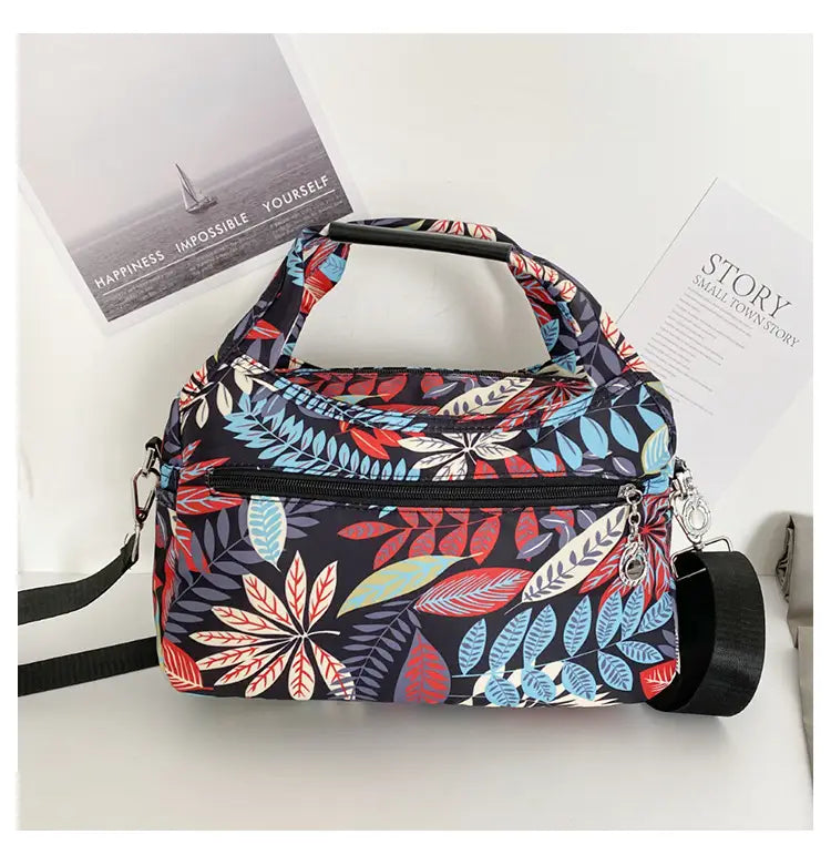 Oxford cloth floral messenger bag with a dark navy base featuring a vibrant red blue and white leaf pattern in an intricate design for a retro shoulder purse.