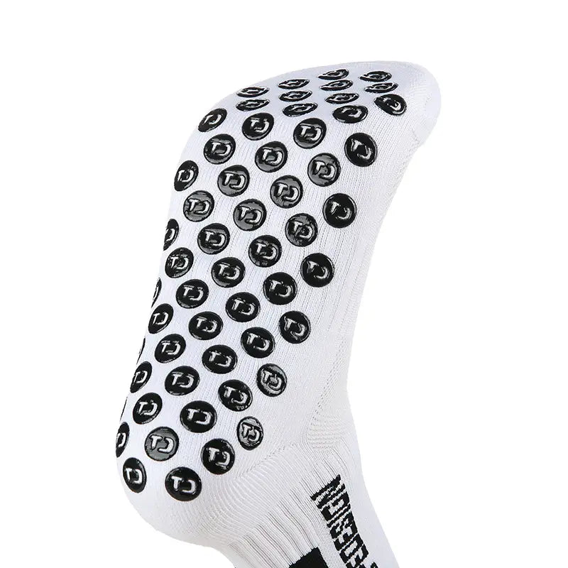 Chaussettes de football antidérapantes blanches avec des pastilles de caoutchouc rondes noires comportant un logo tj sur chaque pastille.