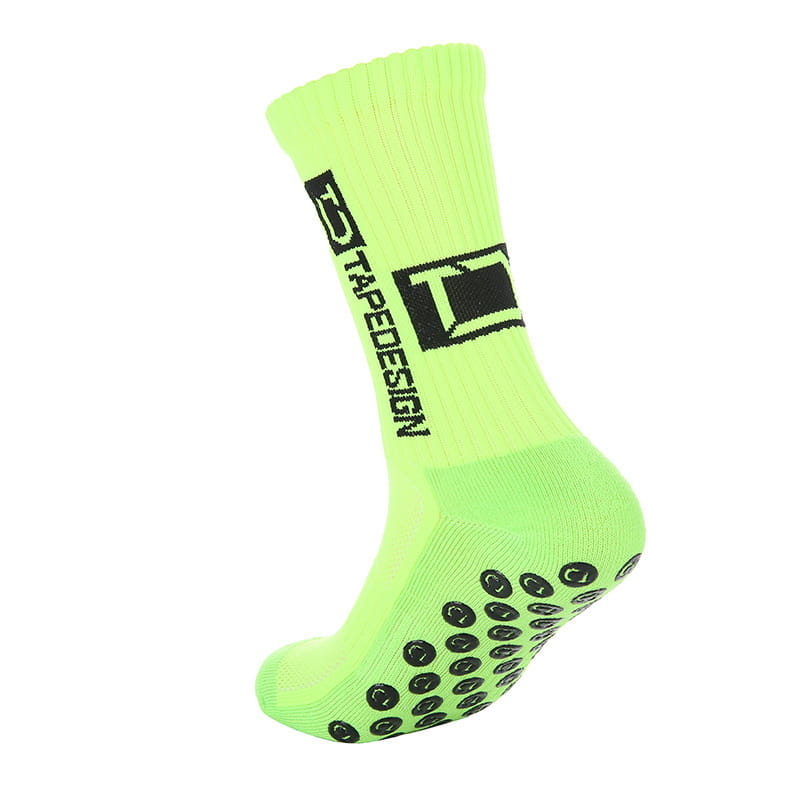 Chaussette de football antidérapante vert fluo vif dotée d’un logo noir et de coussinets texturés circulaires sur la semelle.