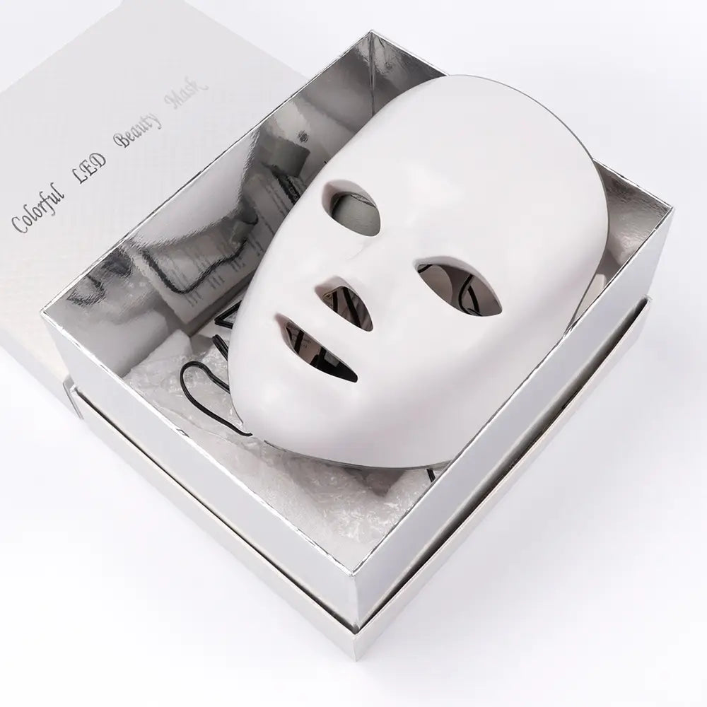 Led facial mask 7 color red light photon skin therapy in white with a sleek minimalist design featuring a smooth surface and cutouts for eyes nose and mouth.