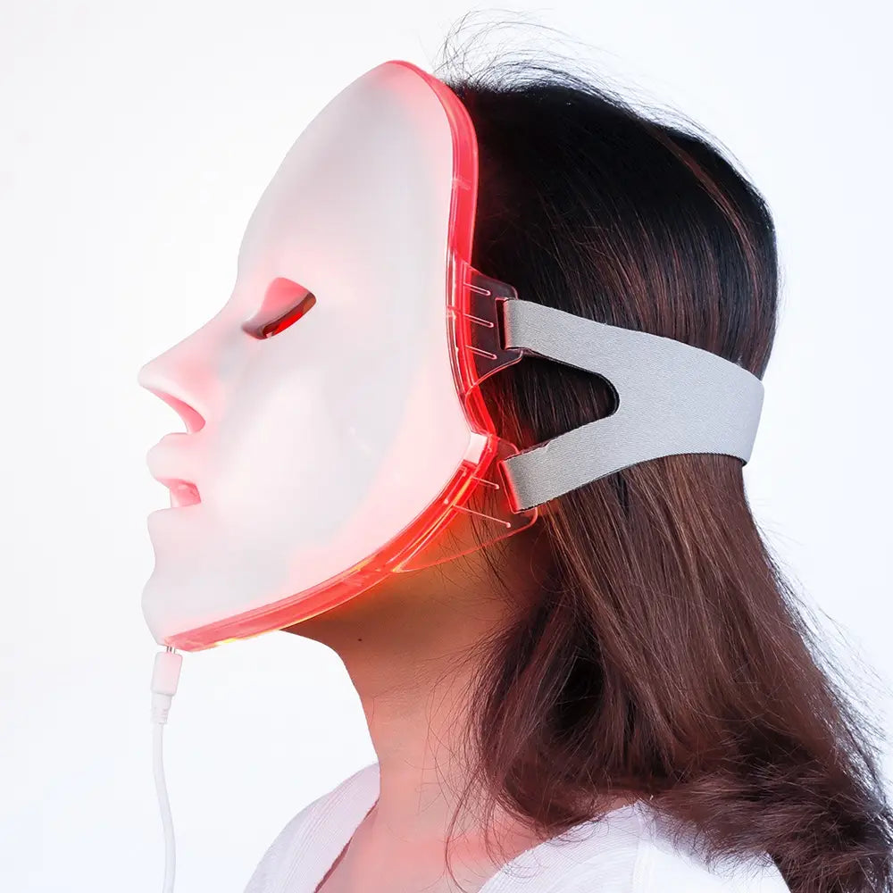 A sleek white led facial mask with red glowing edges and a gray adjustable headband designed for at-home skincare treatments in the led facial mask 7 color red light photon skin therapy product.