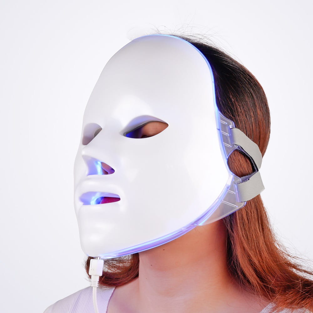 led facial mask white with blue light emitting from eyes nose and mouth areas for 7 color red light photon skin therapy.
