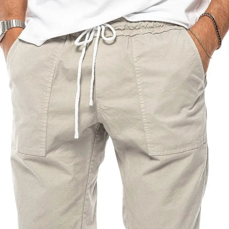 Joggeurs décontractés pour hommes à jambe fuselée beige, avec un cordon de serrage blanc et des coutures apparentes sur les poches cargo.