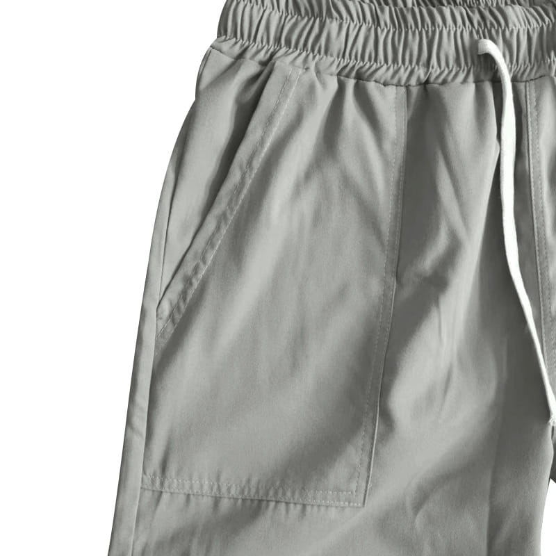 Joggeurs décontractés pour hommes à jambe fuselée gris, avec une coupe ample et des poches latérales visibles, conçus pour le confort et un port au quotidien.