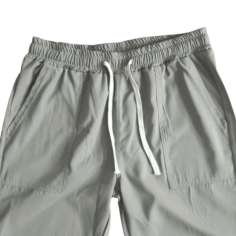 Joggeurs décontractés pour hommes à jambe fuselée gris clair, avec une coupe ample, une ceinture élastique et des cordons de serrage blancs.