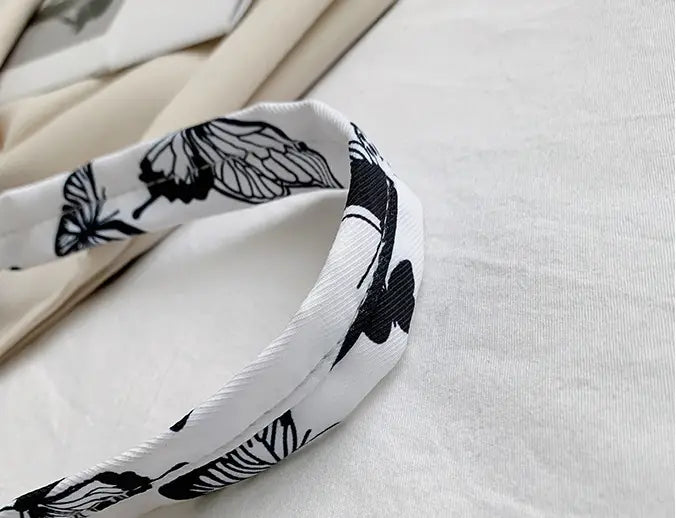 White silk scarf with black butterfly print paired with a white animal print underarm shoulder bag for women.