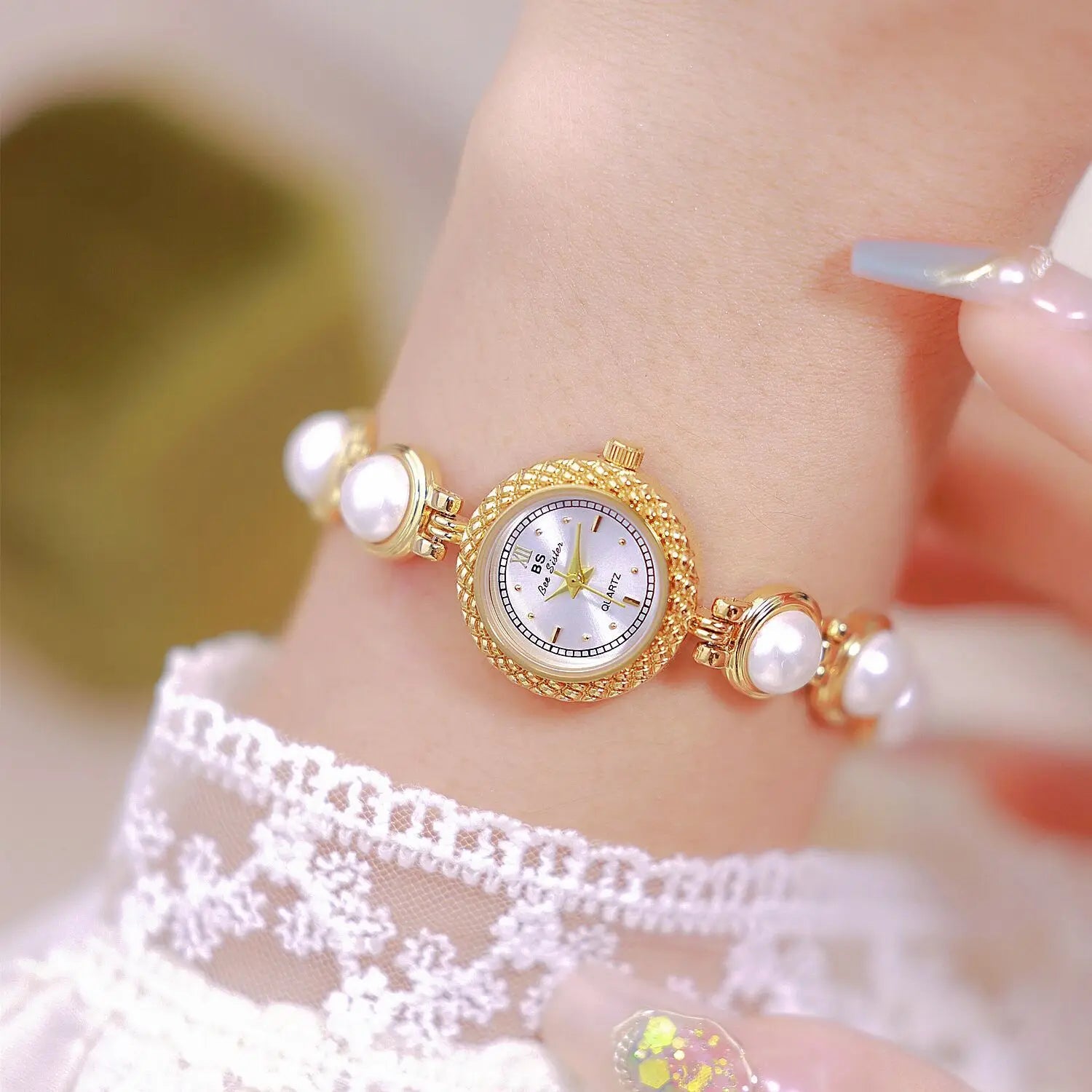 Elegant pearl bracelet quartz watch for women featuring a gold-toned pearl-adorned wristwatch with a delicate textured bezel and white dial.